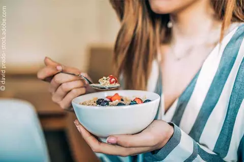 Frau isst Müsli mit Obst