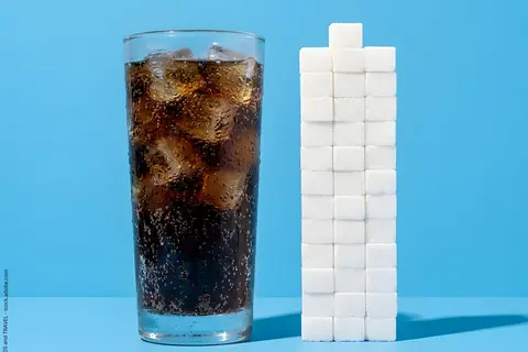 Glas mit Cola und Stapel mit Zuckerwürfeln
