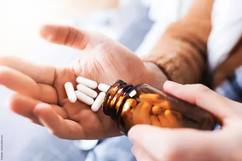 Tabletten werden aus Fläschchen auf Handfläche geleert