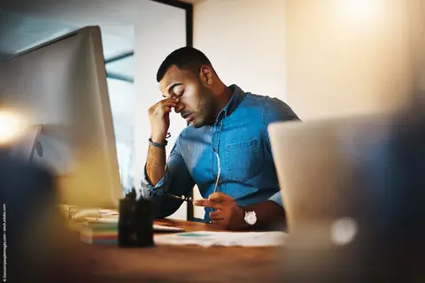 Mann der müde und gestresst vor dem PC sitzt