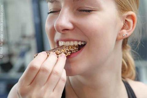Frau isst einen Müsliriegel